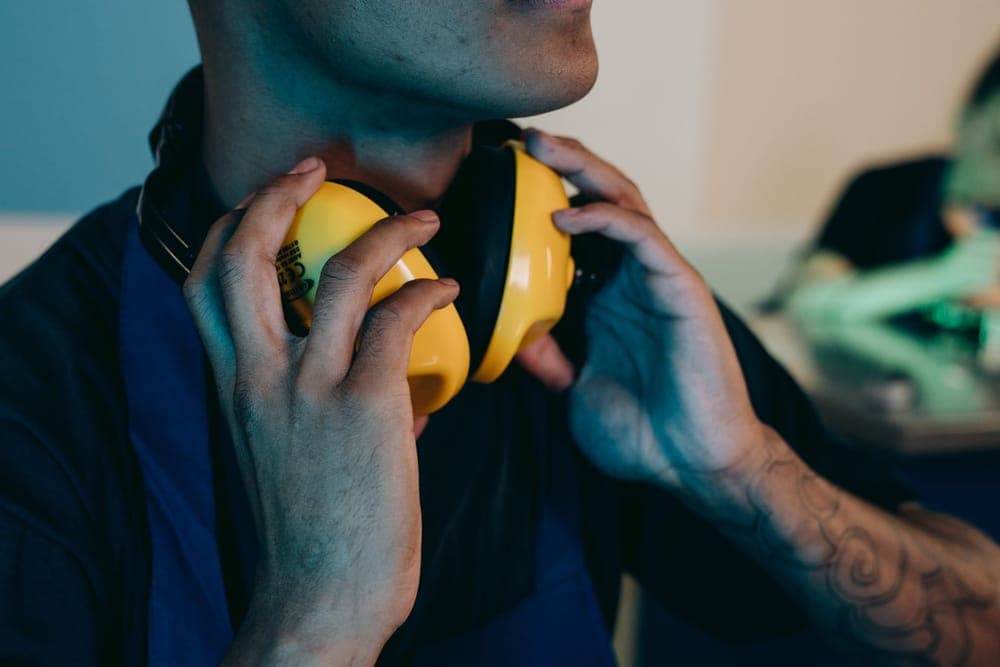 A person settling yellow earmuffs over their ears
