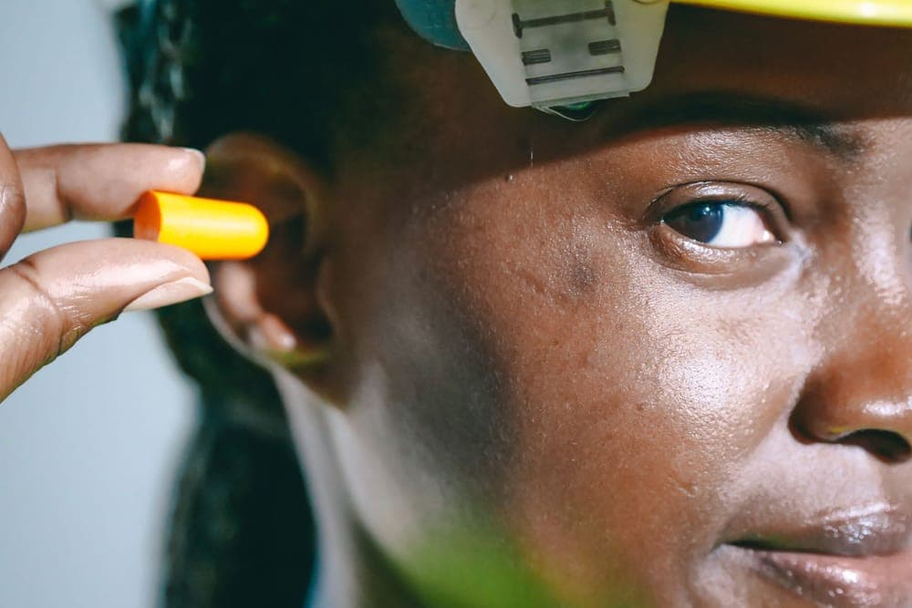 A woman inserting an orange foam earplug