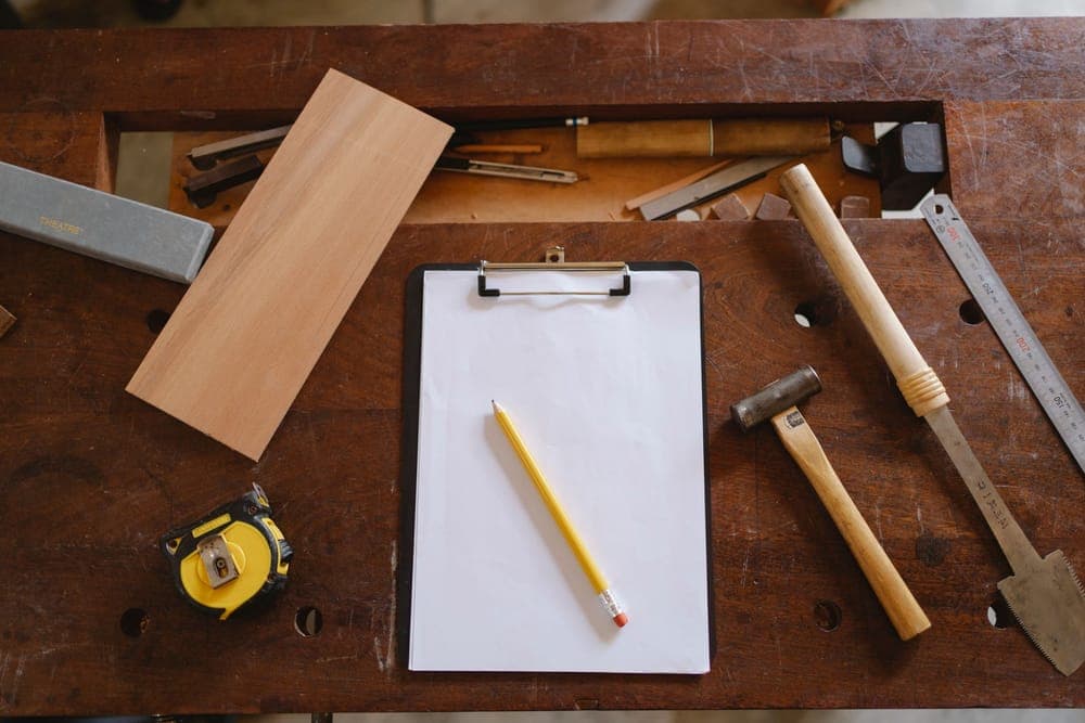 Tools, a tape measure and a clipboard on a wooden workbench