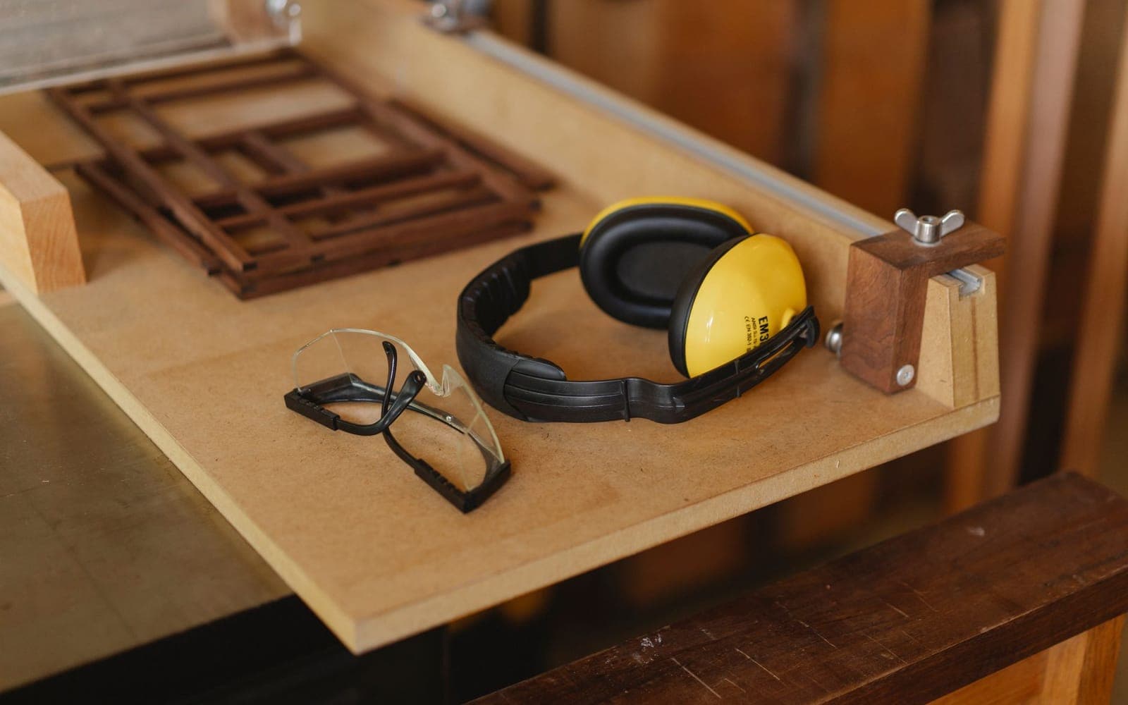 Yellow earmuffs and clear safety glasses resting on a wooden bench