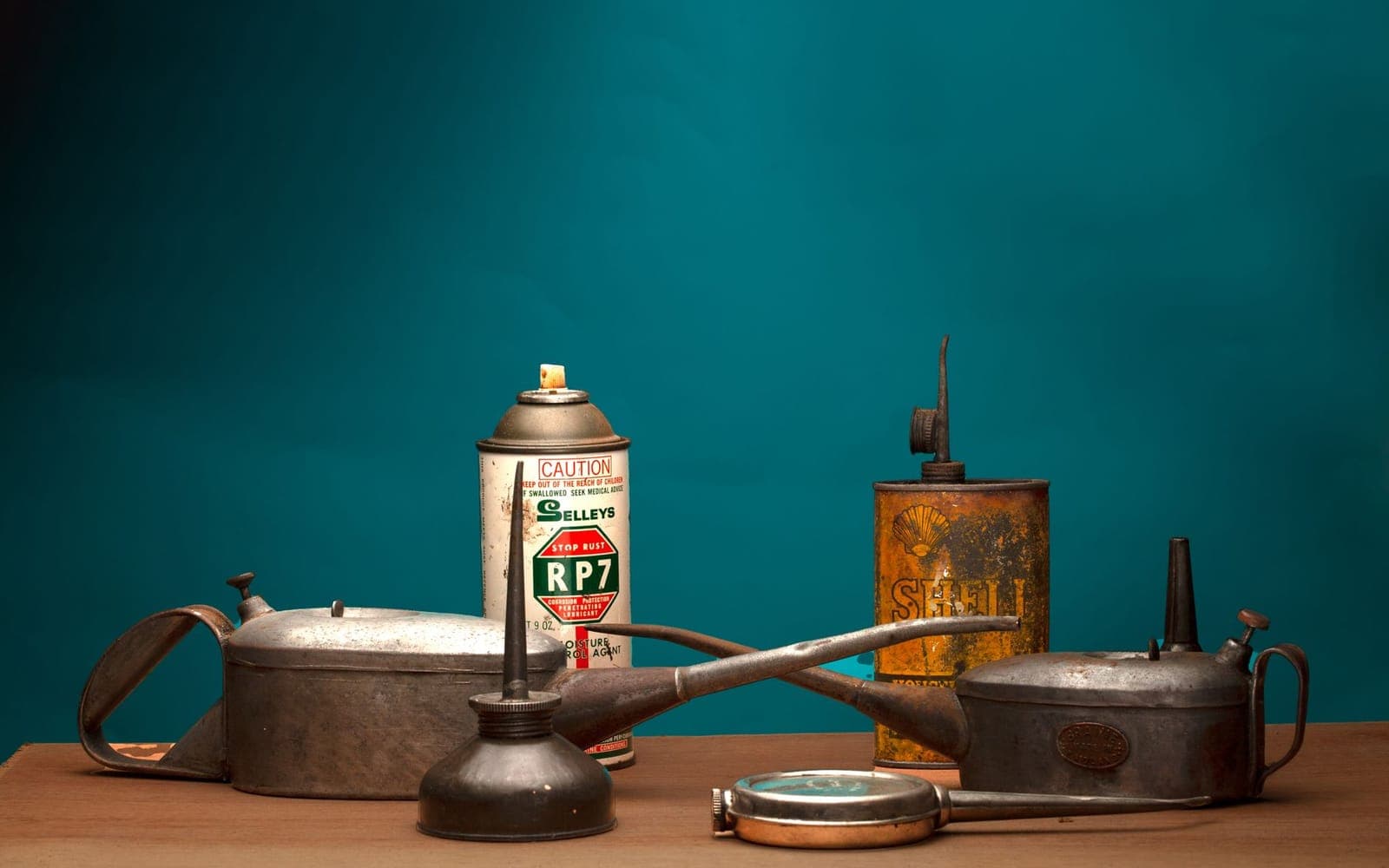 Vintage oil cans and a spray can on a wooden table